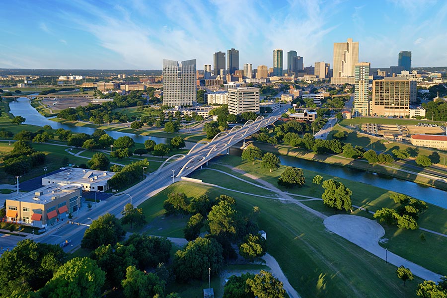 Frisco, TX - Aerial View of Downtown Fort Worth Displaying Many Trees, Buildings, a River on a Sunny Day